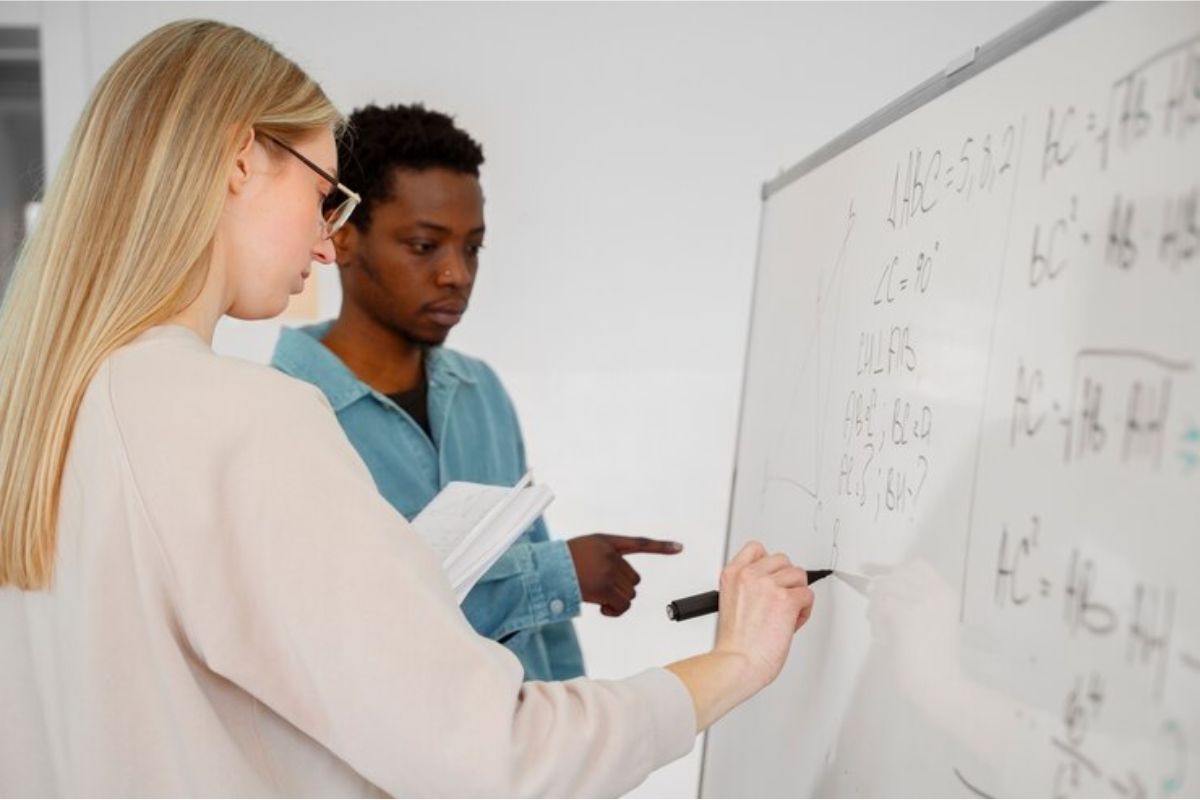 Uma professora explicando na lousa branca algumas questões sobre questões de matemática ETEC 2025