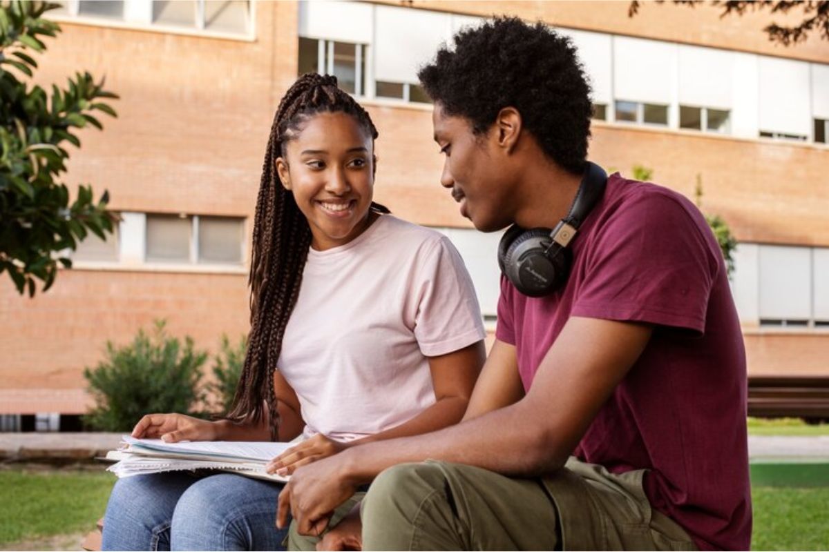 Dois alunos sentados em um banco no pátio da escola, eles falam sobre os Cursos menos concorridos da ETEC 2025