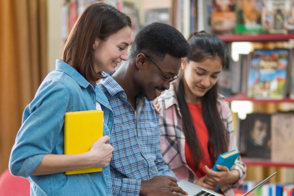 Três estudantes escolhem um livro na livraria