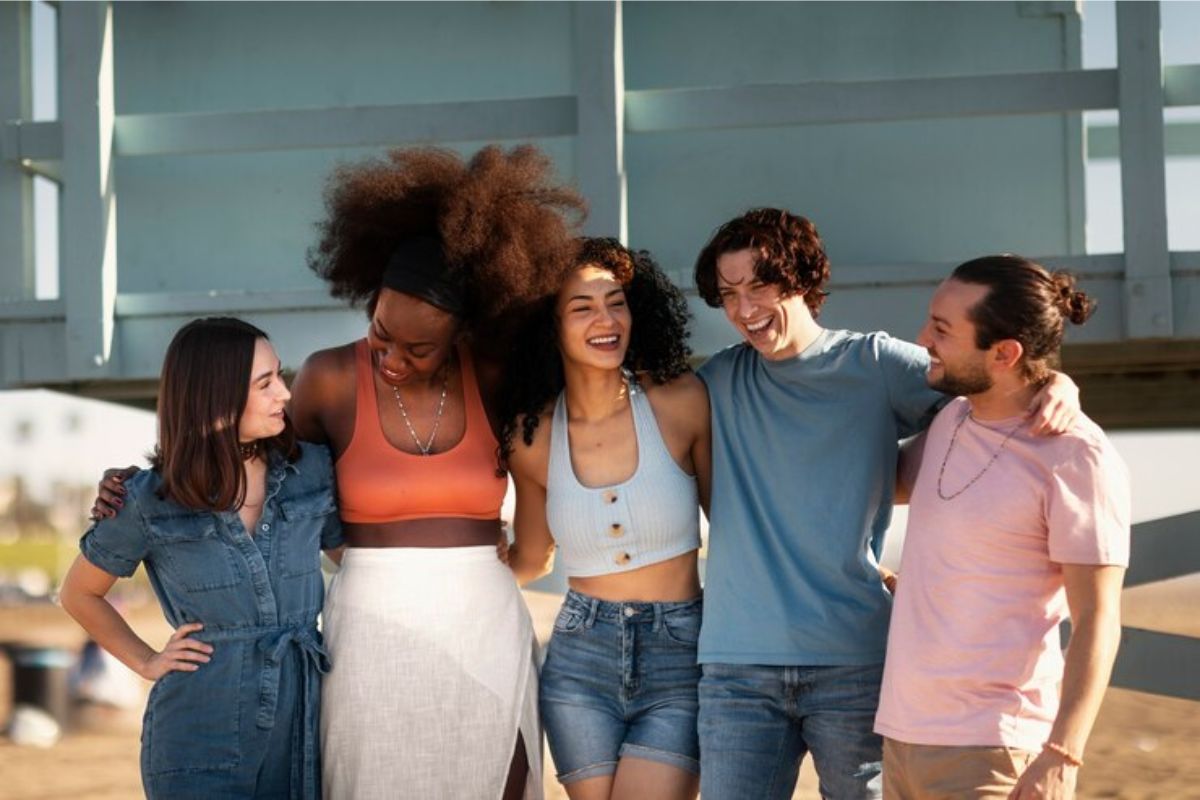 Cinco estudantes na saída do curso se abraçam