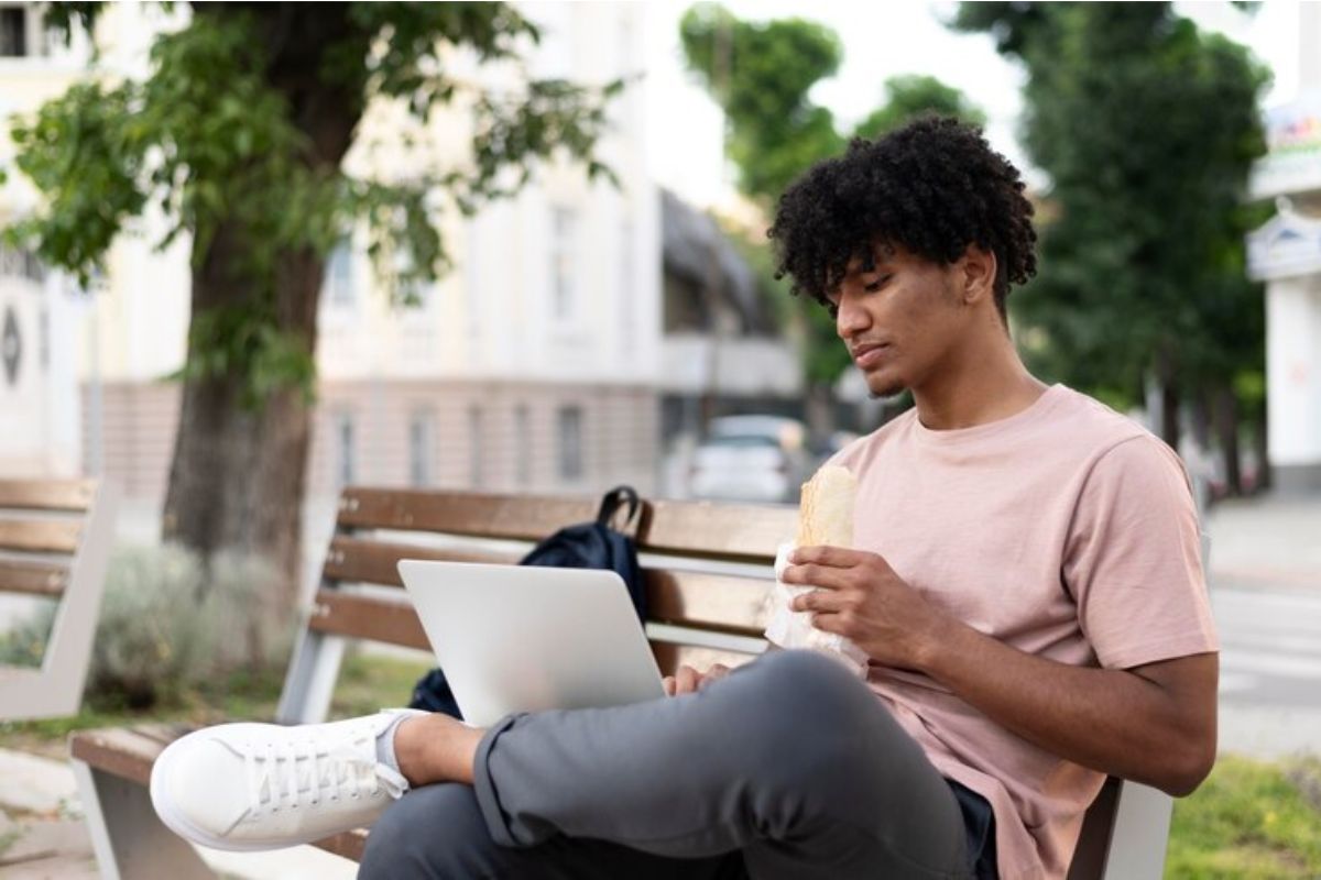 Um estudante sentado em casa com seu notebook aberto pesquisa os cursos da ETEC Guarulhos 2025