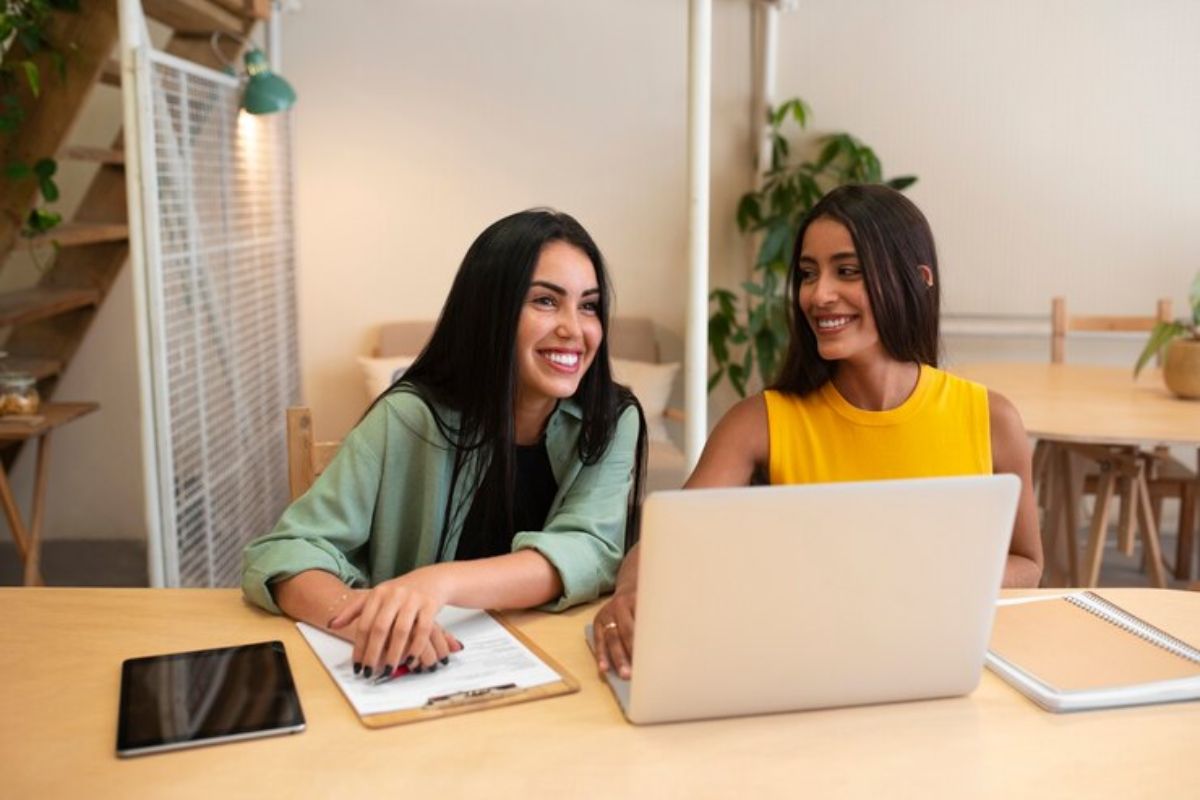 Duas colegas sentadas em frente ao notebook acessam a Área do Candidato ETEC 2025