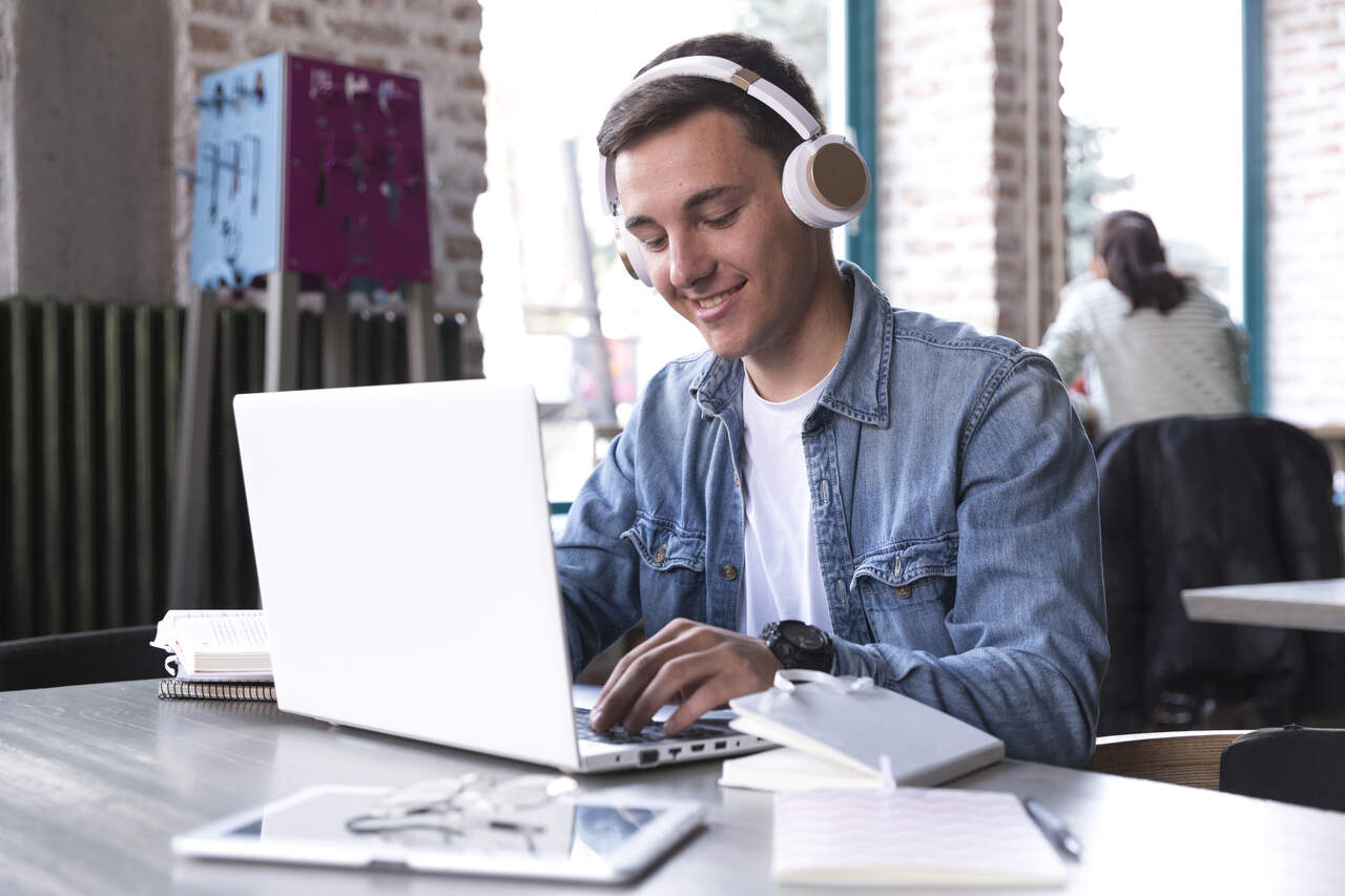 Jovem estuda com fones nos ouvido usando o notebook