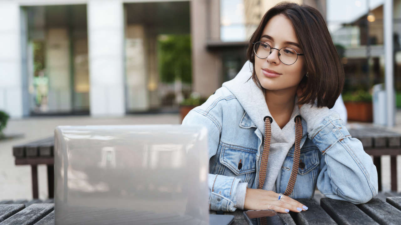 Garota de cabelo curto sentada com laptop na mesa