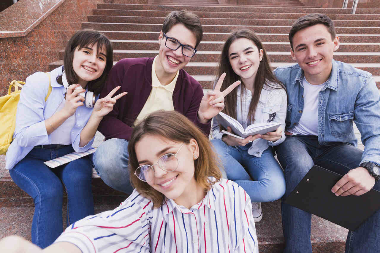 Grupo de adolescentes posam juntos para foto em escadaria da escola 