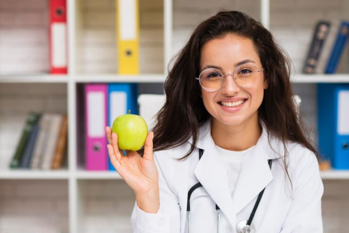 Uma aluna do Curso de Nutrição e Dietética ETEC 2025 com uma maça verde na mão sorrindo