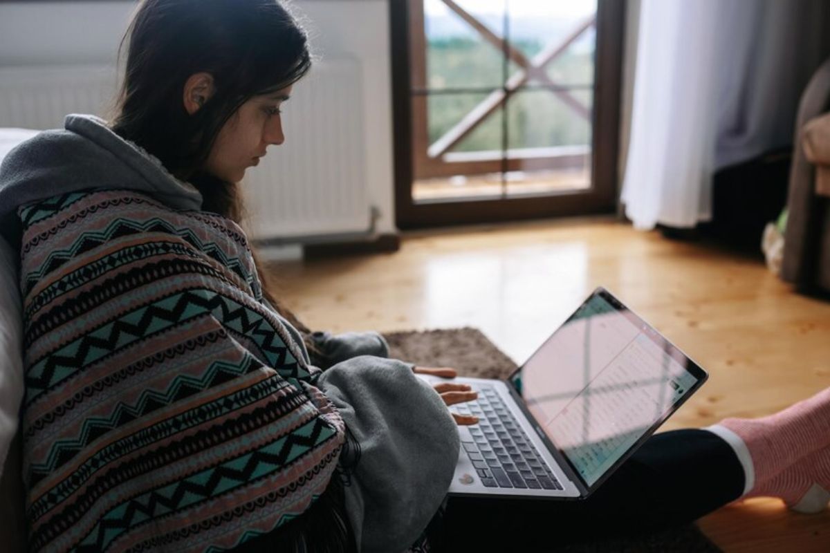 Uma estudante com seu notebook no colo na sala de casa vendo o que estudar para o Vestibulinho ETEC 2025